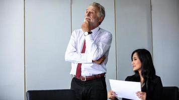 elderly Businessman and business woman sitting in a meeting and checking documents and notebooks on a desk in a meeting room. photo