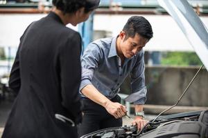 Businessman helping to check and fix a broken woman's car on the side of the road photo