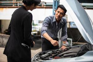 Businessman helping to check and fix a broken woman's car on the side of the road photo