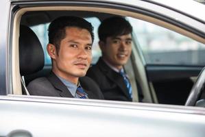 Two business men are driving and looking out of the car window. photo