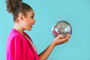 cheerful afro american woman holding in her hands christmas bauble decoration. Christmas, new year, happiness, holidays concept photo