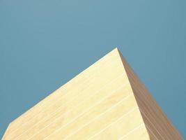 Low angle view of a yellow pyramid structure agaonst blue sky photo