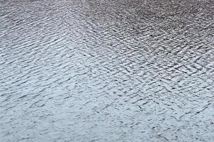 The texture of the water in the river under the influence of wind. A lot of shallow waves on the water surface photo
