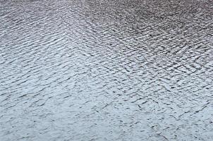 The texture of the water in the river under the influence of wind. A lot of shallow waves on the water surface photo