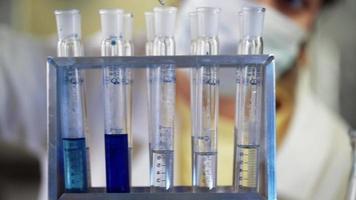 scienziato nel laboratorio fare chimico sperimentare con blu liquido nel test tubi. estrazione dna e molecole. vaccino sviluppo. ricerca, biochimica, farmaceutico medicina concetto. avvicinamento. video