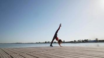 jeune fille caucasienne athlétique dans un débardeur rouge et des leggings lève la jambe en fente. flexibilité d'étirement. video