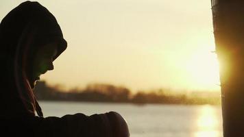 Silhouette of a boxer against the backdrop of a beautiful sunset and a river in an abandoned building, trains blows on a punching bag. Epic video. Motivation. Sports and martial arts. Slow motion. video