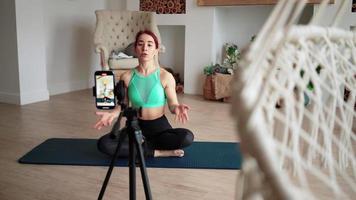 Online learning and live streaming concept. Woman blogger tells how to do aerobic exercise from fitness on phone camera. Athletic girl conducts training via video call. Online training course at home.