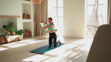 mujer atlética en ropa deportiva haciendo ejercicio en casa, haciendo sentadillas. chica en forma deportiva dedicada a ejercicios aeróbicos de fitness en el dormitorio. salud corporal. concepto de entrenamiento, entrenamiento y bienestar en el hogar. video