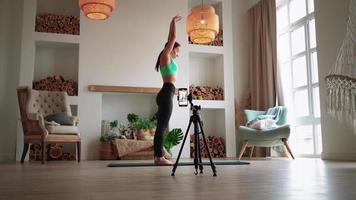 Online learning and live streaming concept. Woman blogger tells how to do aerobic exercise from fitness on phone camera. Athletic girl conducts training via video call. Online training course at home.