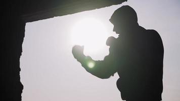 Silhouette eines Boxers auf einem Sonnenuntergangshintergrund. Trainer Schläge. Schattenboxen. Outdoor-Training. Motivationsvideo. Thema gesunder Lebensstil und Sport. Kampfkunst. Boxen. Zeitlupe. video