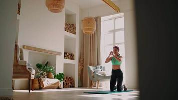 Athletic Woman in Sportswear Exercising at Home, Doing an Exercise Squats. Sporty Fit Girl Engaged in Fitness Aerobic Exercises in Bedroom. Body Health. Home workout, training and wellness concept.