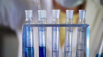 cientista em laboratório fazendo experimento químico com líquido azul em tubos de ensaio. extração de DNA e moléculas. desenvolvimento de vacinas. pesquisa, bioquímica, conceito de medicina farmacêutica. fechar-se. video