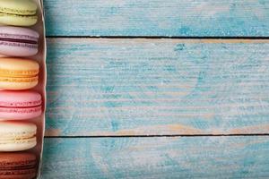 Macaroni cookies of different colors in a box on a blue, old wooden background of blue color. photo