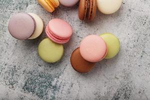 French macaroni cookies of different colors are on the gray table. Still life of confectionery. photo