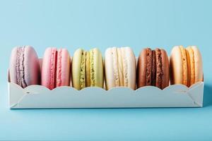 Macaroni cookies of different colors in a white box on a blue background. photo