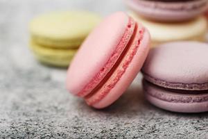 French macaroni cookies of different colors are on the gray table. Still life of confectionery. photo