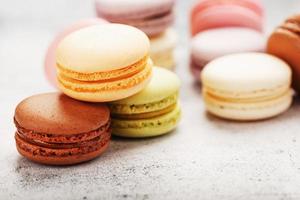 French macaroni cookies of different colors are on the gray table. Still life of confectionery. photo