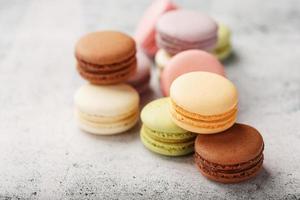 French macaroni cookies of different colors are on the gray table. Still life of confectionery. photo