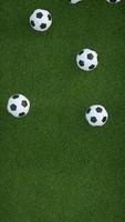 Animation vidéo 4k. ballons de football tombant sur le terrain en herbe.
