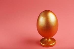 Golden egg on a pink background with a minimalistic concept. photo