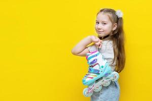 cheerful little girl holds a roller over her shoulder and looks back. copy space on yellow background photo