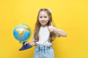 smiling little girl holds a globe in her hand and the second one shows a like, the concept of learning is joy, our future photo