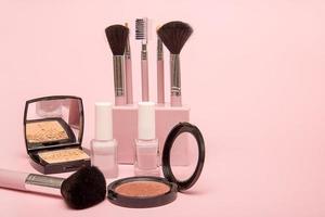 set of makeup brushes, nail polish, powder, blush on a pink background. photo