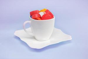 waste plastic lids in a tea cup on a blue background, the concept of recycling, zero waste production photo