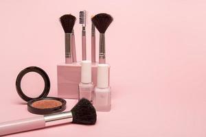 set of makeup brushes, nail polish, blush on a pink background with copy space photo