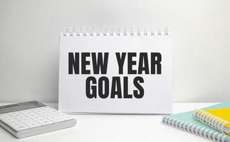 new year goals words on white notebook with colourful notepads and calculator photo
