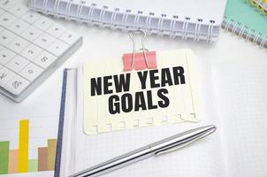 new year goals words on yellow sticker with colourful charts and calculator photo