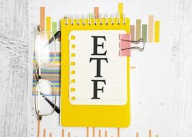 ETF analysis concept. Word on yellow paper and charts photo