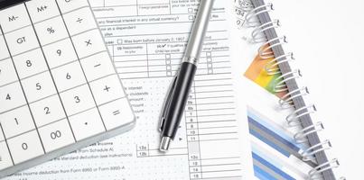 Formulario de declaración de impuestos individual de EE. UU. 1040 con calculadora, bolígrafo y gráficos foto