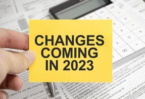 notepad with text Changes Coming in 2023 with calculator and tax forms photo
