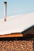 wooden roof of firewood stack shed covered with snow photo