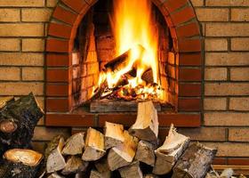 pile of firewood and fire in brick fireplace photo