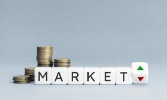 Market word and up and down arrows on block shape and coins stacked. Copy space photo