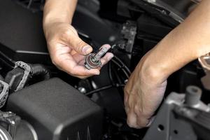 A man hold Xenon car headlights and and inserted into the headlight to replace the broken bulb in engine room , Replacing the headlight bulbs of the car itself service concept photo