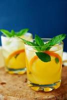 Orange fresh lemonade in glass on dark background photo