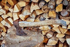 Close up of axe agains firewood background photo