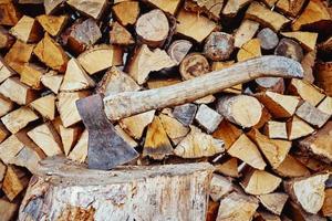 Close up of axe agains firewood background photo