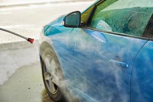 Cleaning car with high pressure water at car wash station photo