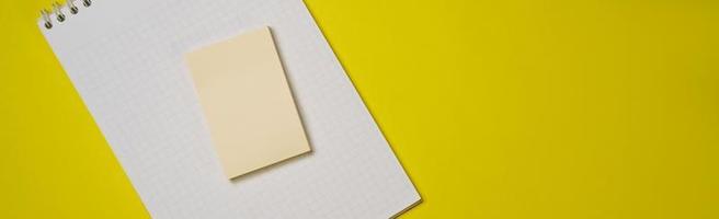 Open blank white notepad on a spiral and stickers on a yellow background. photo