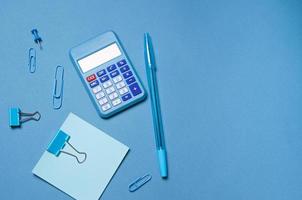 Calculator, stationery accessories on blue background with copy space. Look photo