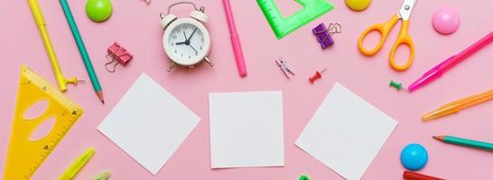 White notepad on spring and stationery school supplies on a pink background photo