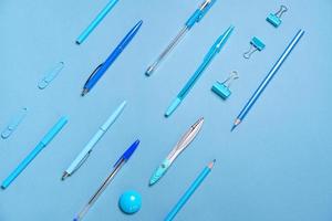 bolígrafos, lápices, brújulas, clips de papel dispuestos en líneas, todo azul y fondo foto