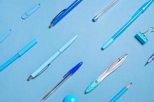 Pens pencils compasses paper clips laid out in lines all blue and background photo