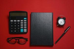 Male black notepad ballpoint pen and calculator, small alarm clock and glasses photo