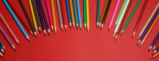 Colored wooden pencils on red background, education concept. photo